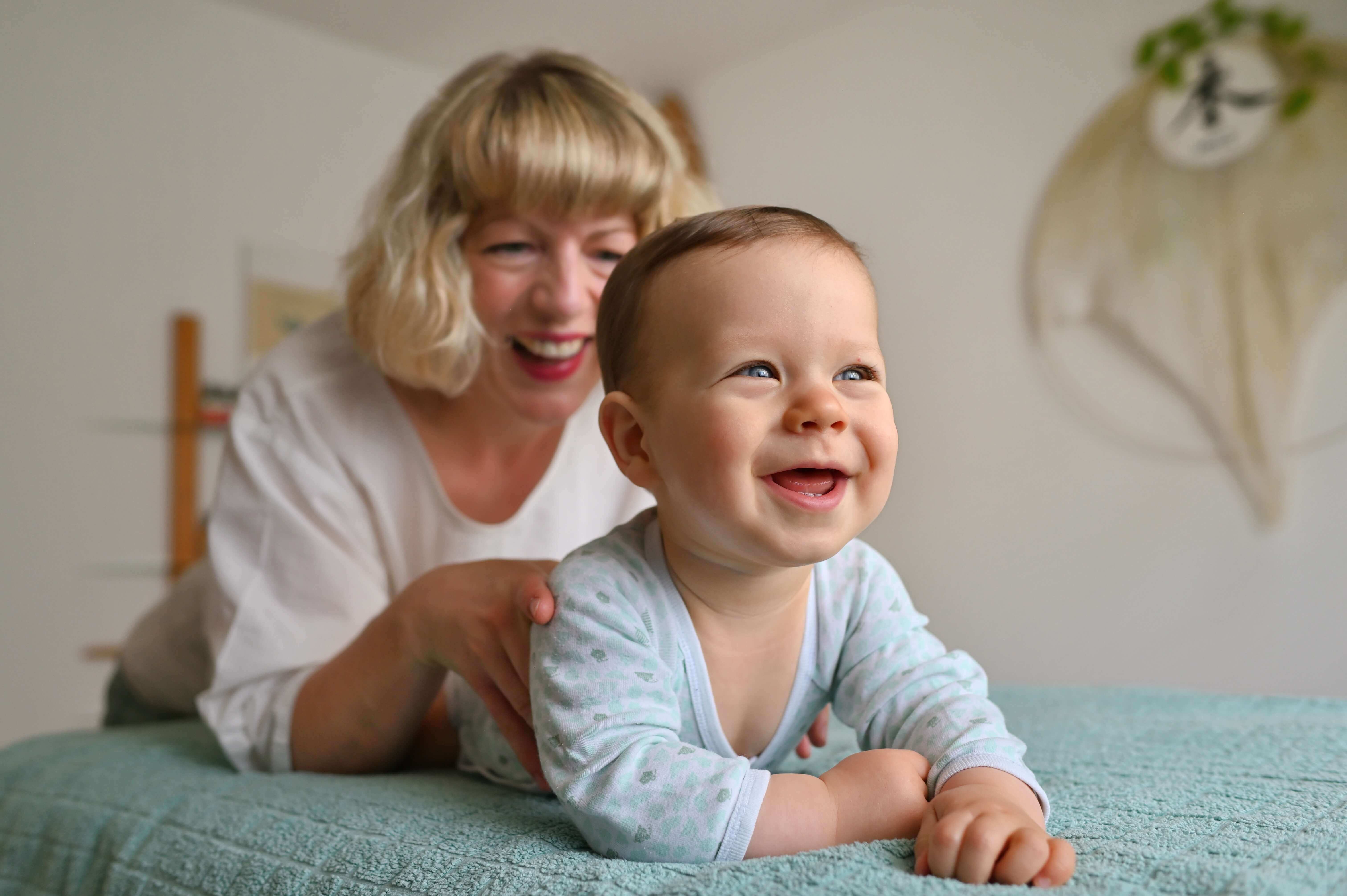 Kinderosteopathie: Katharina Schreiber behandelt ein lachendes Baby in Bauchlage